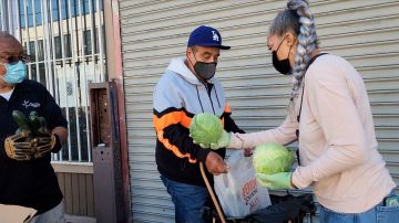 Los voluntarios de Hope On Union en la despensa de alimentos del “Día Vegano” le dan verduras a un residente de Los Ángeles.