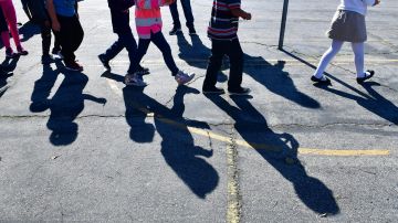 Telfair Elementary school children cast shadows as they arrive at Operation School Bell on February 8, 2019 in Pacoima, California, some thirty minutes drive north of downtown Los Angeles, where the children receive new items such as backpacks, shoes and clothing. - For Jose Razo, principal at Telfair Elementary School in Los Angeles county, his students should spend their time worrying about homework, their grades or playdates. But the harsh reality for more than a quarter of the 720 children at the school is otherwise."Food, somewhere to sleep, something to put on their back: those are the challenges our students are facing," says Razo. "Someone seven or eight years old should not have to worry about that." (Photo by Frederic J. BROWN / AFP) (Photo credit should read FREDERIC J. BROWN/AFP via Getty Images)