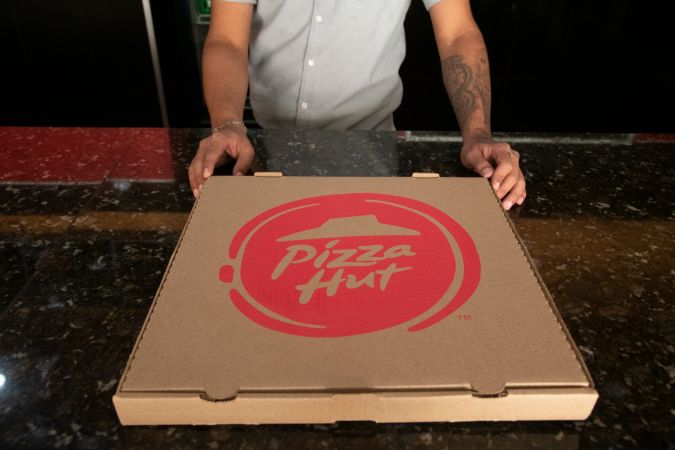CARACAS, VENEZUELA - NOVEMBER 30: A Pizza Hut employee holds a pizza box at a store in las Mercedes on November 30, 2020 in Caracas, Venezuela. CryptoBuyer has become Pizza Hut's payments partner in Venezuela. Customers can make orders for food with bitcoin, dash and CryptoBuyer's own token, XPT. With Venezuela suffering from hyperinflation, the nation is seen as having potential for rising adoption of cryptocurrency as an alternative method of payment and store of value. (Photo by Carlos Becerra/Getty Images)