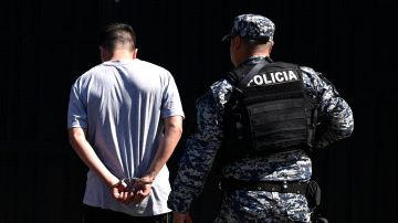 TOPSHOT - A man arrested for alleged gang links is escorted by an officer of the National Civil Police during the state of emergency declared by the Salvadoran government at the San Salvador penal center, on June 22, 2022. - In response to a spate of 87 murders committed between 25 and 27 March, Congress granted a request by President Nayib Bukele to decree a state of emergency, which has been extended until at least the end of July, and has allowed more than 43,000 suspected gang members to be detained without warrants. Organisations such as Amnesty International and the NGO Human Rights Watch have questioned the procedures and called on Bukele to respect human rights. The US government has also expressed concern about "arbitrary" detentions and "deaths in custody". (Photo by MARVIN RECINOS / AFP) (Photo by MARVIN RECINOS/AFP via Getty Images