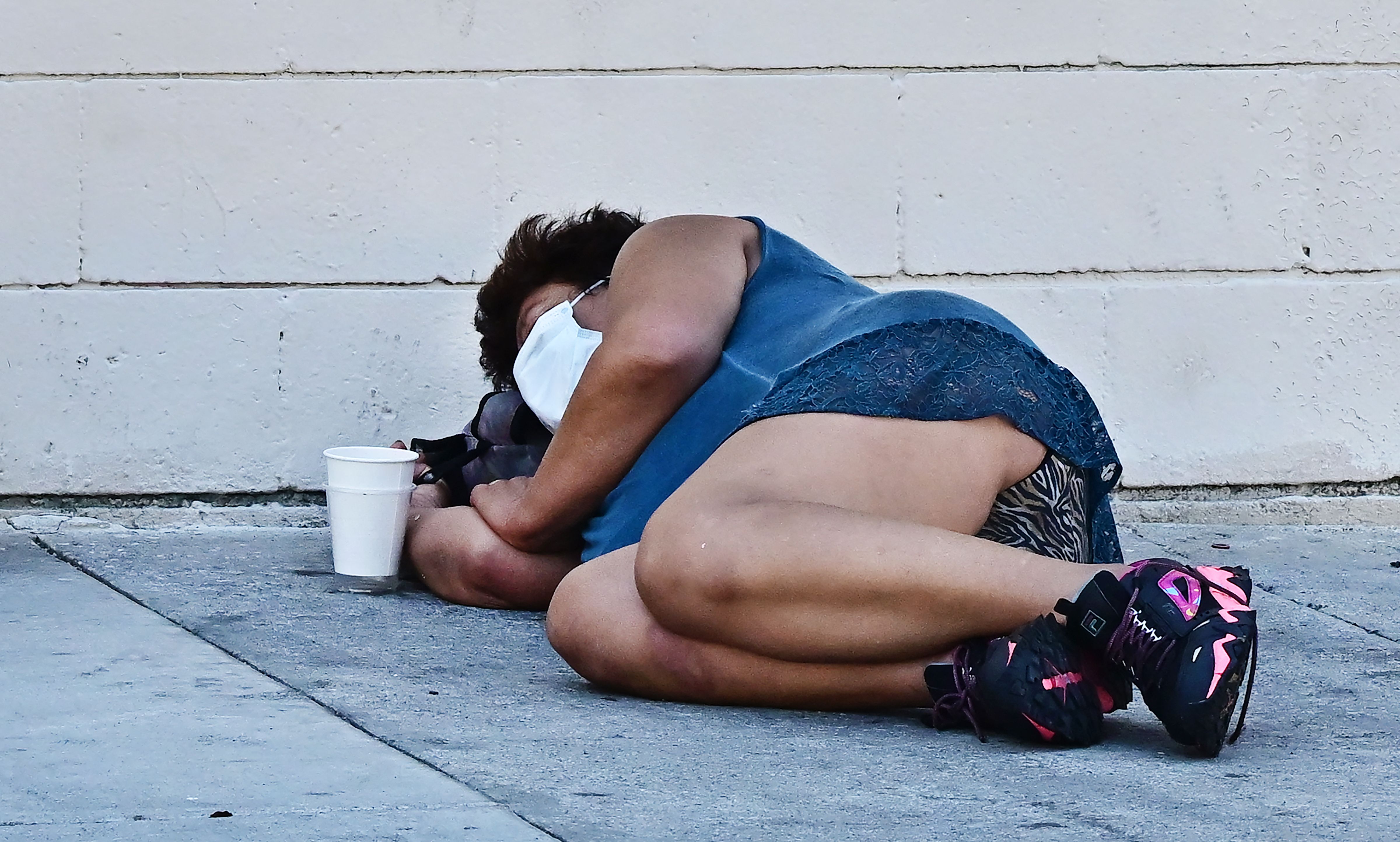 A woman sleeps on a sidewalk on August 16, 2023, in Los Angeles, California, where homelessness has seen a 10 percent surge compared to last year. A recent report from the Los Angeles Homeless Services Authority reveals an estimate of 42,260 people living on the streets of Los Angeles without shelter, as the homeless population has more than doubled over the past decade. (Photo by Frederic J. BROWN / AFP) (Photo by FREDERIC J. BROWN/AFP via Getty Images)