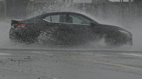 A vehicle splashes up water during heavy rains from Tropical Storm Hilary, in south Los Angeles, California, on August 20, 2023. Hurricane Hilary weakened to a tropical storm on August 20, 2023, as it barreled up Mexico's Pacific coast, but was still likely to bring life-threatening flooding to the typically arid southwestern United States, forecasters said. Authorities reported at least one fatality in northwestern Mexico, where Hilary lashed the Baja California Peninsula with heavy rain and strong winds. (Photo by Robyn BECK / AFP) (Photo by ROBYN BECK/AFP via Getty Images)