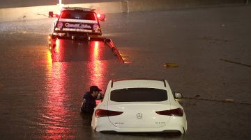 SUN VALLEY, CALIFORNIA - AUGUST 20: A tow truck driver attempts to pull a stranded car out of floodwaters on the Golden State Freeway as tropical storm Hilary moves through the area on August 20, 2023 in Sun Valley, California. Southern California is under a first-ever tropical storm warning as Hilary impacts parts of California, Arizona and Nevada. All California state beaches have been closed in San Diego and Orange counties in preparation for the impacts from the storm which was downgraded from hurricane status. (Photo by Justin Sullivan/Getty Images)