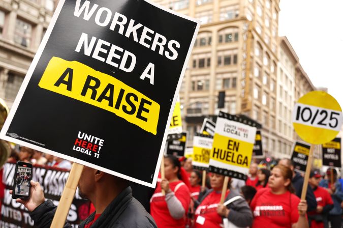 LOS ANGELES, CALIFORNIA - OCTOBER 25: Hotel workers with Unite Here Local 11 march, as one person holds a 'Workers Need A Raise' sign, through downtown L.A. calling for a `fair contract’ from numerous major hotels in the region on October 25, 2023 in Los Angeles, California. Thousands marched in the demonstration as striking workers from five hotels were joined by workers from ‘dozens more’ hotels as contract talks continue. (Photo by Mario Tama/Getty Images)