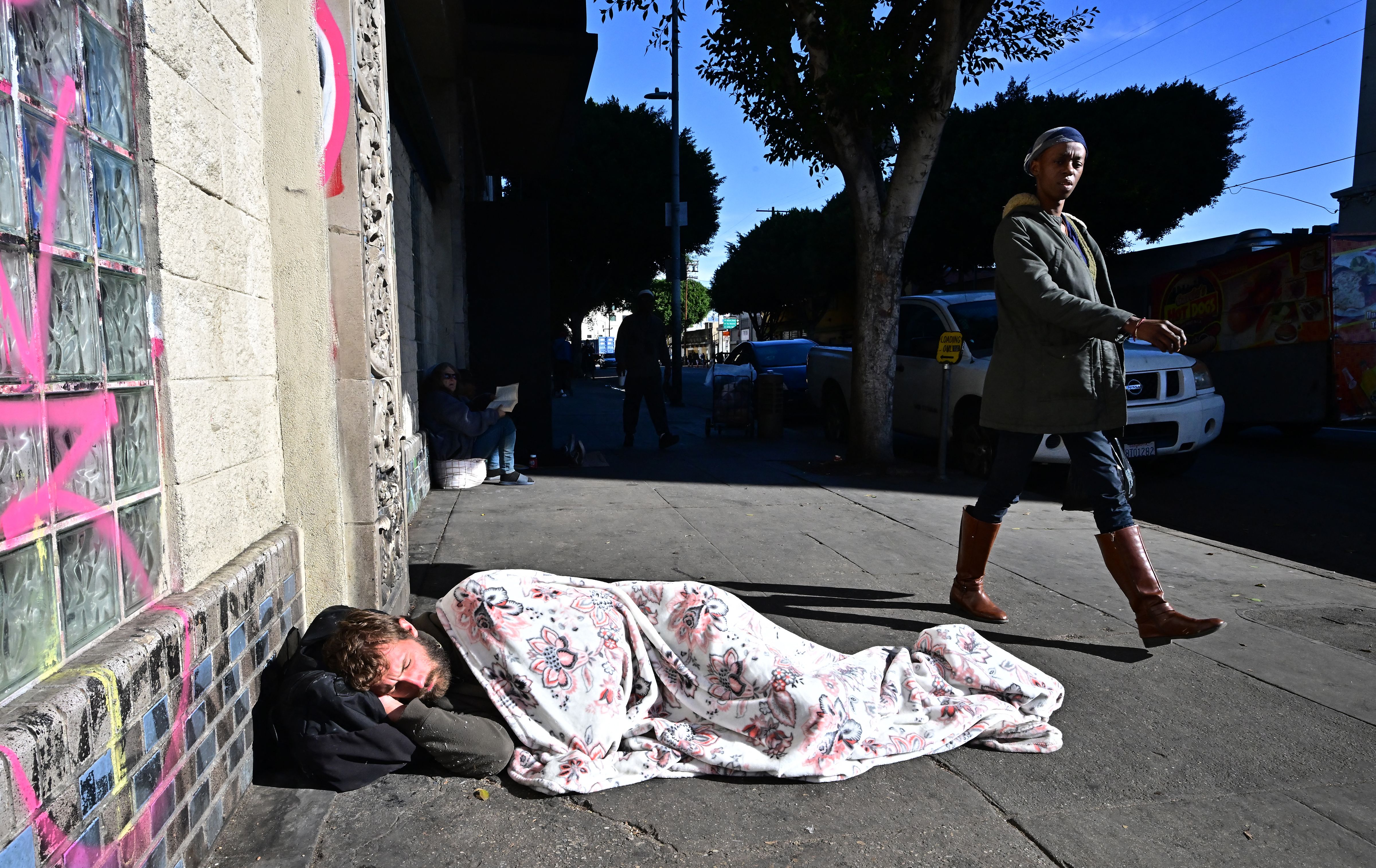 TOPSHOT - A homeless man sleeps on the sidewalk in Downtown Los Angeles on November 22, 2023. (Photo by Frederic J. BROWN / AFP) (Photo by FREDERIC J. BROWN/AFP via Getty Images)
