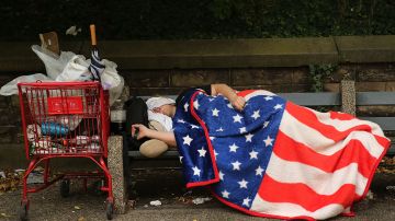 Un desamparado durmiendo en un banco en la calle en Nueva York.