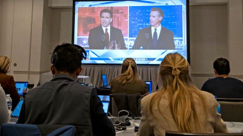 Gavin Newsom y Ron DeSantis se ven en la pantalla de la sala de prensa durante el debate realizado por Fox News.