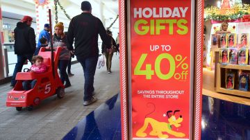 Christmas week shoppers walk past signs offering sales at a Montebello shopping mall in Montebello, California on December 22, 2016. Shopping the week before Christmas can pay off as The National Retail Federation says they expect retailers will again be competitive on value and price in the final days. / AFP / Frederic J. BROWN (Photo credit should read FREDERIC J. BROWN/AFP via Getty Images)
