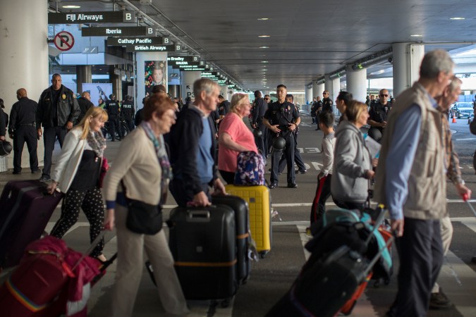 LOS ANGELES, CA - FEBRUARY 04: International travelers pass police officers keeping demonstrators and counter demonstrators apart during protests in support of a ruling by a federal judge in Seattle that grants a nationwide temporary restraining order against the presidential order to ban travel to the United States from seven Muslim-majority countries, at Tom Bradley International Terminal at Los Angeles International Airport on February 4, 2017 in Los Angeles, California. (Photo by David McNew/Getty Images)