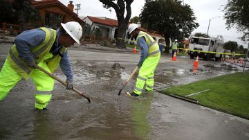 LOS ANGELES, CA - FEBRUARY 27: Los Angeles Department of Water and Power (LADWP) workers shovel water and mud that is being pumped out of a massive sinkhole on West Boulevard on February 27, 2017 in Los Angeles, California. California has been battered by a string of powerful rainstorms that have casued an estimated $600 million in damages to roadways and bridges. (Photo by Justin Sullivan/Getty Images)