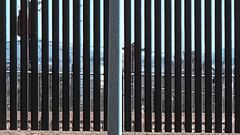 Migrantes cruzan la cerca de púas cerca del muro fronterizo en Texas para entregarse a las autoridades de Estados Unidos.