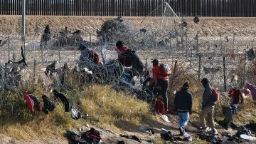 Migrantes cruzan la cerca de púas cerca del muro fronterizo en Texas para entregarse a las autoridades de Estados Unidos.