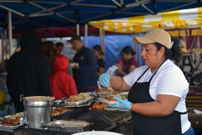 A cook prepares tacos at a street vending stand in the Pinata District in Downtown Los Angeles on March 23, 2019. - On January 1, 2019, the Safe Vending Act (SB946) went into effect in the state of California prohibiting the arrest or finning of street vendors and leaving to municipalities the power to establish permits, sanitation and security issues. The Los Angeles County has set a year to negotiate with vendors the terms on which the law is going to be applied. Some 50,000 street vendors are estimated to work in Los Angeles, a $504 million industry according to a 2015 study by the Economic Roundtable. The LA County issued a municipal ordinance that designates specific areas where the vendors must operate. The ordinance does not include areas such as Memorial Coliseum, the Staples Center, Dodger Stadium, Rose Bowl Stadium and the Hollywood Walk of Fame. Street vendors have mixed feelings about the legalization of their work. At the same time they feel freed of being against the law and harassed by police giving them tickets and seizing their goods; they are concerned about having to abide to health regulations, permits and limited areas. (Photo by Agustin PAULLIER / AFP) (Photo credit should read AGUSTIN PAULLIER/AFP via Getty Images)