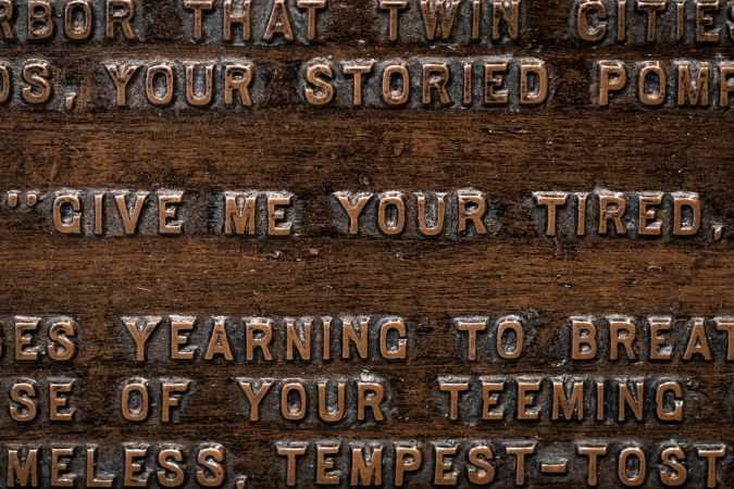 NEW YORK, NY - AUGUST 14: Words from 'The New Colossus' poem by Emma Lazarus are engraved on a replica bronze plaque inside the Statue of Liberty Museum on Liberty Island August 14, 2019 in New York City. On Tuesday, acting Director of the Citizenship and Immigration Services Ken Cuccinelli reworked the words of the Emma Lazarus poem The New Colossus as he defended the Trump administrations immigration policies. The poem appears on a plaque inside The Statue of Liberty. The 1883 poem by Lazarus is often cited as an inspiration statement about America's attitude toward immigrants. (Photo by Drew Angerer/Getty Images)