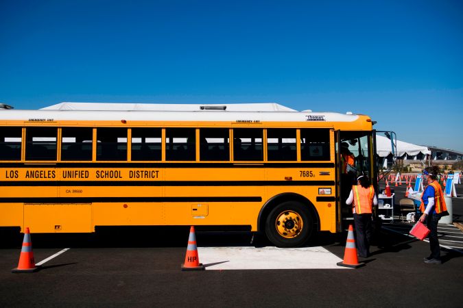 Vaccination site workers board a school bus transporting education workers as it arrives at a mass vaccination site in a parking lot at Hollywood Park adjacent to SoFi stadium during the Covid-19 pandemic on March 1, 2021 in Inglewood, California. - The vaccination site is part of a plan from the Los Angeles Unified School District (LAUSD) and State of California to reopen all district elementary schools by mid-April. (Photo by Patrick T. FALLON / AFP) (Photo by PATRICK T. FALLON/AFP via Getty Images)