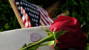 A penny, indicating to the family of the fallen soldier that someone has stopped by to pay their respects, is seen next to a rose on a headstone at Los Angeles National Cemetery on Memorial Day, in Los Angeles, California on May 31, 2021. (Photo by Chris Delmas / AFP) (Photo by CHRIS DELMAS/AFP via Getty Images)