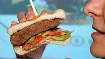 A woman holds a cut half of a plant-based patty with a meaty taste, made and cooked by a robot according to customer requirements, offered by Israeli fast food brand BBB in the Israeli coastal town of Herzliya on December 28, 2021. - The Israeli fast food restaurant BBB is serving up a veggie steak made and cooked by a robot that tailors ingredients and cooking time to customer tastes. Customers can use an app to choose the amount of vegetable protein or fat in their "steak", as well as its size and how they want it cooked, she said. The "robot chef", which is the size of a large oven, can make three different steaks simultaneously -- though a human staff member makes up the burgers. (Photo by JACK GUEZ / AFP) (Photo by JACK GUEZ/AFP via Getty Images)