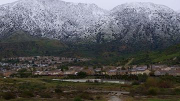 TOPSHOT - Houses sit below snow covered mountains in the Angeles National Forest in Sylmar, California, on February 25, 2023. - A major storm with a blizzard warning for parts of Southern California is expected to deliver damaging rain and snow at elevations lower than normal in Los Angeles County. (Photo by Allison Dinner / AFP) (Photo by ALLISON DINNER/AFP via Getty Images)