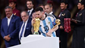 LUSAIL CITY, QATAR - DECEMBER 18: Lionel Messi of Argentina kisses the FIFA World Cup Winners' Trophy while holding the adidas Golden Boot award after the FIFA World Cup Qatar 2022 Final match between Argentina and France at Lusail Stadium on December 18, 2022 in Lusail City, Qatar. (Photo by Catherine Ivill/Getty Images)