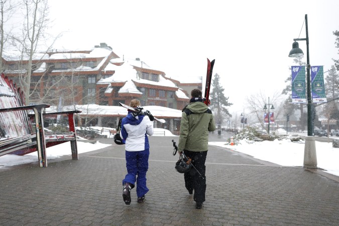 SOUTH LAKE TAHOE, CALIFORNIA - MARCH 21: People carry skis as they walk towards a resort on March 21, 2023 in South Lake Tahoe, California. As a 12th atmospheric river hits California, the Lake Tahoe region is getting more snow. According to the UC Berkeley Central Sierra Snow Lab, this snow season has become the second snowiest season on record since the lab first started keeping records 77 years ago. More than 56.4 feet of snow has fallen in the Sierras this season surpassing the storm of 1982-83 which had 55.9 feet. (Photo by Justin Sullivan/Getty Images)
