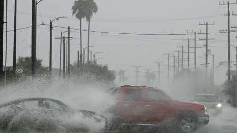 Vehicles splash up water during heavy rains from Tropical Storm Hilary, in south Los Angeles, California, on August 20, 2023. Hurricane Hilary weakened to a tropical storm on August 20, 2023, as it barreled up Mexico's Pacific coast, but was still likely to bring life-threatening flooding to the typically arid southwestern United States, forecasters said. Authorities reported at least one fatality in northwestern Mexico, where Hilary lashed the Baja California Peninsula with heavy rain and strong winds. (Photo by Robyn BECK / AFP) (Photo by ROBYN BECK/AFP via Getty Images)