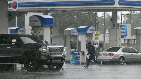 A person runs outside a gas station during heavy rains from Tropical Storm Hilary, in south Los Angeles, California, on August 20, 2023. Hurricane Hilary weakened to a tropical storm on August 20, 2023, as it barreled up Mexico's Pacific coast, but was still likely to bring life-threatening flooding to the typically arid southwestern United States, forecasters said. Authorities reported at least one fatality in northwestern Mexico, where Hilary lashed the Baja California Peninsula with heavy rain and strong winds. (Photo by Robyn BECK / AFP) (Photo by ROBYN BECK/AFP via Getty Images)
