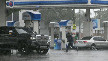 A person runs outside a gas station during heavy rains from Tropical Storm Hilary, in south Los Angeles, California, on August 20, 2023. Hurricane Hilary weakened to a tropical storm on August 20, 2023, as it barreled up Mexico's Pacific coast, but was still likely to bring life-threatening flooding to the typically arid southwestern United States, forecasters said. Authorities reported at least one fatality in northwestern Mexico, where Hilary lashed the Baja California Peninsula with heavy rain and strong winds. (Photo by Robyn BECK / AFP) (Photo by ROBYN BECK/AFP via Getty Images)