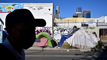 A man walks past tents housing the homeless on November 22, 2023 in Los Angeles, California, where skyrocketing rents in recent years has led to an increasing rise in the number of unhoused people. Some 75,500 people live on the streets of Los Angeles and its sprawling suburbs, according to a January survey. The figure is up 70 percent since 2015, in a city where sometimes shocking levels of inequality are on daily display. (Photo by Frederic J. BROWN / AFP) (Photo by FREDERIC J. BROWN/AFP via Getty Images)