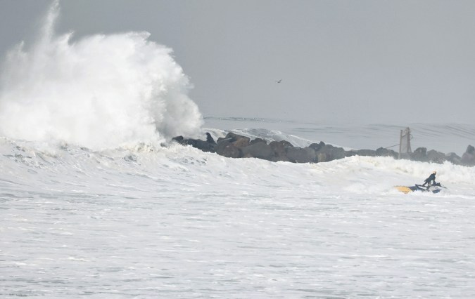 EL SEGUNDO, CALIFORNIA - DECEMBER 29: A person operates a jet ski as a large wave crashes over a jetty near the beach on December 29, 2023 in El Segundo, California. Dangerous surf churned up by storms in the Pacific is impacting much of California’s coastline with coastal flooding possible in some low-lying areas. (Photo by Mario Tama/Getty Images)