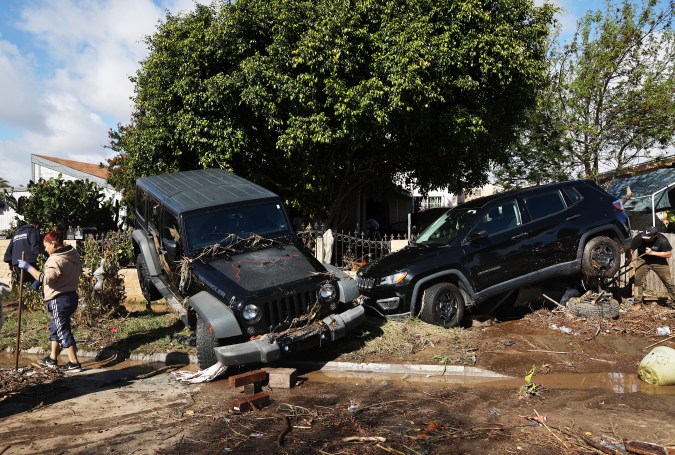 SAN DIEGO, CALIFORNIA - JANUARY 23: A person (R) works to help tow away a vehicle dislodged by flooding the day after an explosive rainstorm caused flooding in areas of San Diego County on January 23, 2024 in San Diego, California. The intense rains forced dozens of rescues while flooding roadways and homes and knocking out electricity for thousands of residents. (Photo by Mario Tama/Getty Images)