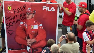 A man takes a photograph of Scuderia Ferrari's supporters as they hold a banner that reads, "Keep fighting Schumi " referring to former F1 legend Michael Schumacher, severely injured in December 2013 in a skiing accident in France, at the Autodromo Nazionale circuit in Monza on September 4, 2014 ahead of the Italian Formula One Grand Prix on September 7. AFP PHOTO / GIUSEPPE CACACE (Photo credit should read GIUSEPPE CACACE/AFP via Getty Images)