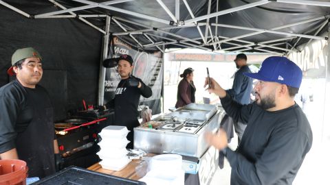 Pedro Escobar (izq.) inmigrante de Teocaltiche, Jalisco da trabajo a cuatro personas en su puesto de tacos y carnitas.