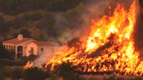 FILE - In this Thursday, Dec. 14, 2017, file photo provided by the Santa Barbara County Fire Department, flames from a back firing operation underway rise behind a home off Ladera Lane near Bella Vista Drive in Santa Barbara, Calif. The largest wildfire on record in California, the Thomas fire, was declared contained on Friday, Jan. 12, 2018, days after mud on the coastal mountain slopes it scorched crashed down on homes during a storm, killing at least 18 people. (Mike Eliason/Santa Barbara County Fire Department via AP, File)