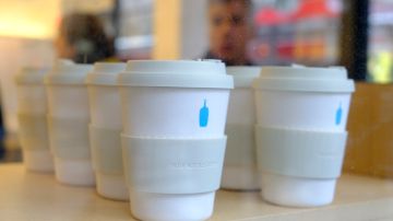 In this Thursday, Dec. 12, 2019 photo, reusable $16 takeaway ecocups are displayed for sale in the window of a Blue Bottle Coffee cafe in San Francisco. The Oakland-based chain says it's getting rid of disposable cups at two locations next year, as part of a pledge to go “zero-waste” at its 70 U.S. locations by the end of 2020. (AP Photo/Eric Risberg)