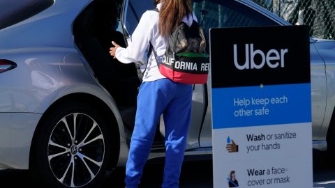 A traveler rides in the back of an Uber vehicle at Los Angeles International Airport in Los Angeles Friday, Nov. 13, 2020. Signs posted asks passengers to maintain 6 ft (2 m.) distance from other travelers. California has become the second state to record 1 million confirmed coronavirus infections. The governors of California, Oregon and Washington issued travel advisories Friday, urging people entering their states or returning from outside the states to self-quarantine to slow the spread of the coronavirus. (AP Photo/Damian Dovarganes)