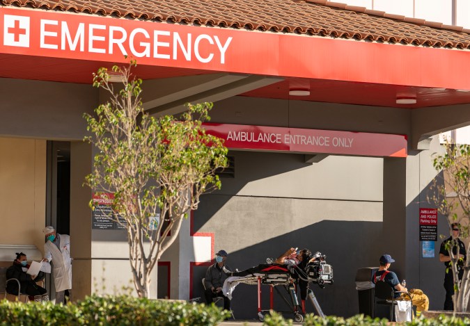 FILE - In this Dec. 18, 2020 file photo an unidentified patient receives oxygen on a stretcher, while Los Angeles Fire Department Paramedics monitor him outside the Emergency entrance, waiting for admission at the CHA Hollywood Presbyterian Medical Center in Los Angeles. California hospitals are facing increasingly difficult decisions about which services to postpone amid a crushing load of coronavirus patients. Intensive-care beds are full in Southern California and the Central Valley, with statewide availability at only 1.1%. (AP Photo/Damian Dovarganes,File)