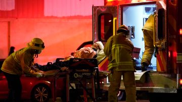 Los Angeles Fire Department paramedics move an injured person into an ambulance after a car crashed against a parked pizza oven trailer on Sunset Boulevard in Los Angeles on Saturday, Dec. 26, 2020. Two people in were transported to a hospital, according to firefighters. (AP Photo/Damian Dovarganes)