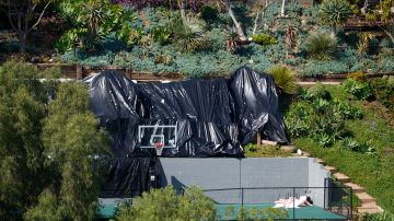 Residential homes use tarps to prevent property damage to the backyard of a home with a tennis and basketball court in Los Angeles, Wednesday, Feb. 21, 2024. (AP Photo/Damian Dovarganes)