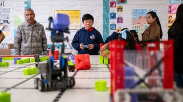 Obed Ortiz, centro, y Jorge Ortiz, izquierda, practican mover un robot durante el taller de robótica en la escuela Magnolia Science Academy en Santa Ana.