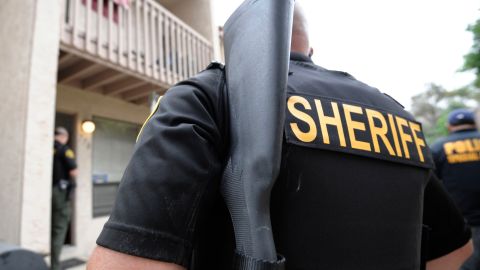 This Aug. 11, 2011 photo shows law enforcement officers waiting outside a home while serving a warrant at the home in Vista, Calif. State, federal and county officers served warrants in San Diego county on people suspected of smuggling drugs illegally into Mexico from the U.S. Authorities speculate that it was easier for smugglers to unload large batches of pills at those loosely regulated pharmacies than to distribute them in small amounts through American street dealers. (AP Photo/Denis Poroy)