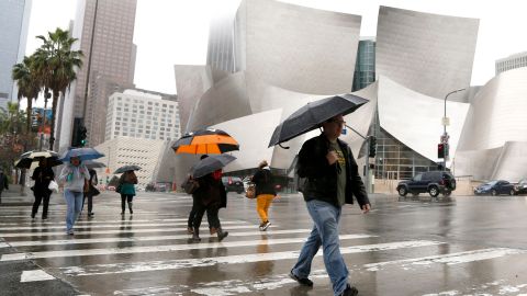 Pedestrians cross a rainy street in downtown Los Angeles on Monday, Feb. 6, 2017. California's winter keeps getting wetter as the first in the latest round of storms moves ashore, bringing heavy rain and powerful winds. The National Weather Service says rain is making for slick roads and reduced visibility for commuters across Southern California. (AP Photo/Nick Ut)