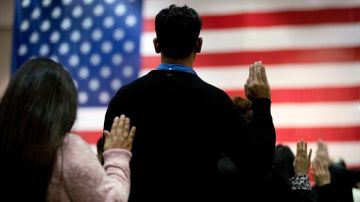 FILE - In this Feb. 15, 2017 file photo, people take the oath of citizenship during a naturalization ceremony at the Los Angeles Convention Center. In a Los Angeles ceremony Wednesday, Sept. 20, 2017, more than 9,000 new American citizens will hear a newly recorded message from President Donald Trump welcoming them to the country and urging them to help others assimilate to help keep the country "safe, strong and free." It is the first time the message from Trump will be played at the massive swearing-in ceremonies held each month in Southern California. (AP Photo/Jae C. Hong, File)