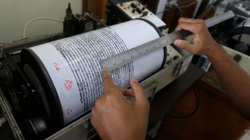 An official looks a seismograph at an observation post near a recent volcanic eruption in Carita, Indonesia, Thursday, Dec. 27, 2018. Indonesia has widened the no-go zone around an island volcano that triggered a tsunami on the weekend, killing hundreds of people in Sumatra and Java. (AP Photo/Achmad Ibrahim)