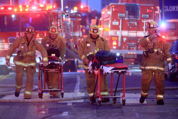 FILE - In this Saturday, May 16, 2020 file photo, Los Angeles Fire Department firefighters push gurneys at the scene of a structure fire that injured multiple firefighters, according to a fire department spokesman. Federal investigators on Monday, May 18, 2020 joined the investigation of an explosion at a downtown Los Angeles hash oil manufacturer that injured 12 firefighters during the weekend. The Bureau of Alcohol, Tobacco, Firearms and Explosives said in a statement that its National Response Team was activated and its experts will work jointly with the Los Angeles Fire Department in processing the scene. (AP Photo/Damian Dovarganes, File)