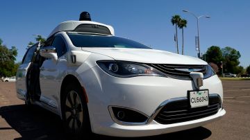 A Waymo minivan arrives to pick up passengers for an autonomous vehicle ride, Wednesday, April 7, 2021, in Mesa, Ariz. Waymo, a unit of Google parent Alphabet Inc., is one of several companies testing driverless vehicles in the U.S. But it's the first offering lifts to the public with no humans at the wheel who can take over in sticky situations. (AP Photo/Ross D. Franklin)