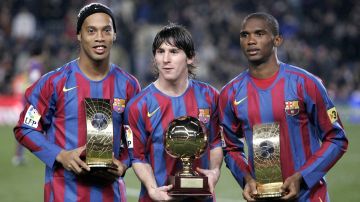 FILE - In this Dec. 20, 2005 file photo Barcelona's Brazilian soccer player Ronaldinho, left, and Samuel Eto'o, from Cameroon, right, show their FIFA world player trophies and Argentinean Leo Messi, center, with his Golden Boy Trophy before their Spanish League soccer match against Celta Vigo at Nou Camp Stadium in Barcelona, Spain. Lionel Messi's time at Barcelona appears to be over. Barcelona announced Thursday Aug. 5, 2021 that Lionel Messi will not stay with the club. He is leaving after 17 successful seasons in which he propelled the Catalan club to glory, helping it win numerous domestic and international titles since debuting as a teenager.(AP Photo/Manu Fernandez, File)