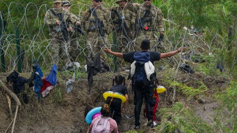 FILE - A migrant gestures to Texas National Guards standing behind razor wire on the bank of the Rio Grande river, seen from Matamoros, Mexico, May 11, 2023. (AP Photo/Fernando Llano, File)