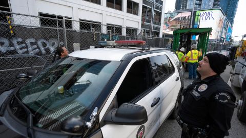 Los Angeles Police officers guard the exterior of an unfinished complex of high-rise towers that have recently been vandalized with graffiti and used for dangerous social media stunts after the developer ran out of money is seen in downtown Los Angeles Friday, Feb. 16, 2024. The three towers have become an embarrassment in a high-profile area that includes Crypto.com Arena, home of major sports teams and events such as the Grammys, as well as the Los Angeles Convention Center and the L.A. Live dining and events complex. (AP Photo/Damian Dovarganes)