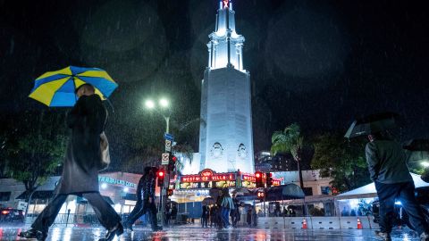 FILE - People walk in the rain past the Fox Theater on Feb. 6, 2024, in the Westwood area of Los Angeles. California's current rainy season got off to a slow start but has rebounded with recent storms that have covered mountains in snow and unleashed downpours, flooding and mudslides. The water content of the vital Sierra Nevada snowpack has topped 80% of normal to date while downtown Los Angeles has already received more than an entire year's average annual rainfall. (AP Photo/Ethan Swope, File)