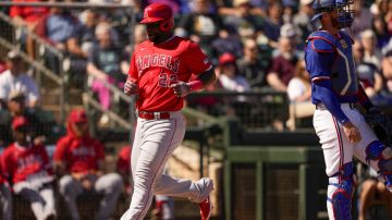 Los Angeles Angels' Miguel Sanó scores on a double from Logan O'Hoppe as Texas Rangers catcher Jonah Heim, right, stands away from the plate during the first inning of a spring training baseball game Monday, March 4, 2024, in Surprise, Ariz. (AP Photo/Lindsey Wasson)
